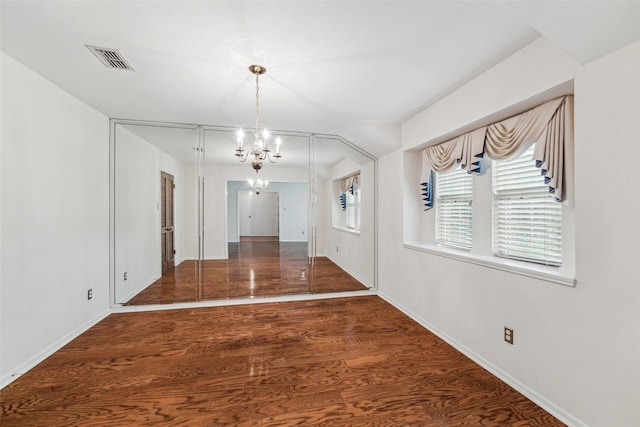 unfurnished dining area with a chandelier, wood finished floors, and baseboards