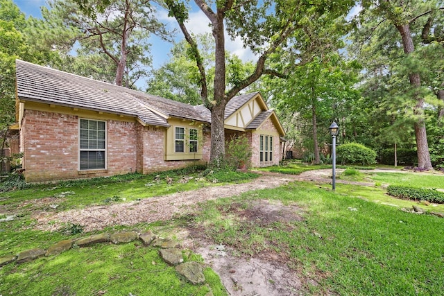 view of side of home featuring brick siding and a lawn
