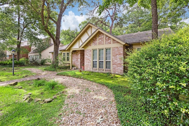 view of front of property with brick siding, a front lawn, and a shingled roof