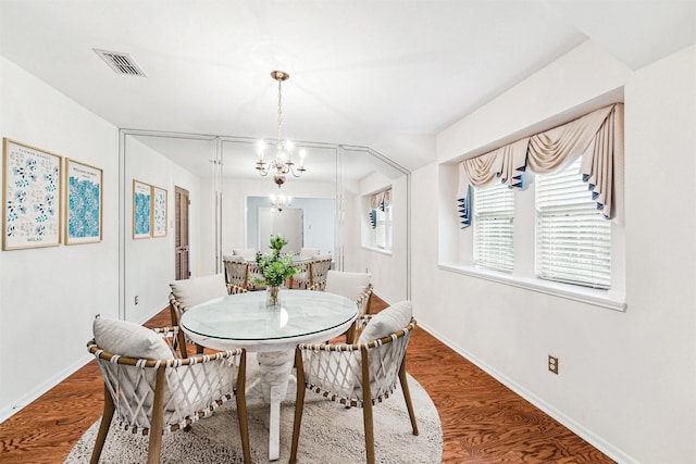 dining space featuring a chandelier, baseboards, and wood finished floors