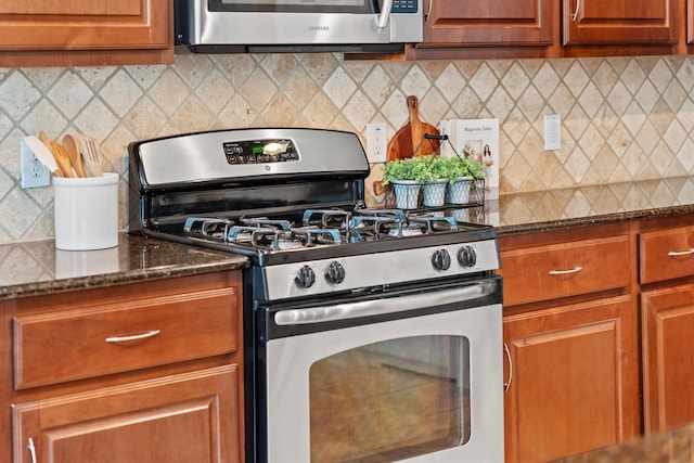 kitchen with stainless steel appliances, decorative backsplash, dark stone counters, and brown cabinetry