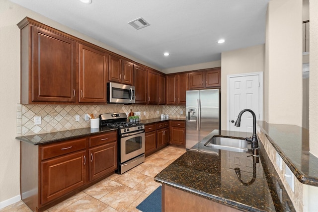 kitchen with appliances with stainless steel finishes, a sink, dark stone countertops, tasteful backsplash, and recessed lighting
