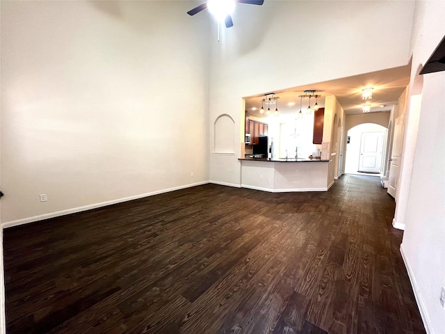 13842 Evansdale Ln, Houston, TX 77083 - unfurnished living room with dark wood-style flooring, arched walkways, ceiling fan, baseboards, and a high ceiling
