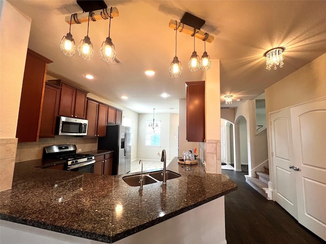 13842 Evansdale Ln, Houston, TX 77083 - kitchen featuring stainless steel appliances, a sink, arched walkways, a peninsula, and backsplash