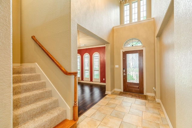 106 Arrowhead Dr, Lake Jackson, TX 77566 - foyer entrance featuring plenty of natural light, a textured wall, a high ceiling, stairway, and baseboards