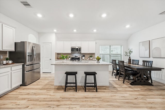kitchen with appliances with stainless steel finishes, light wood finished floors, recessed lighting, decorative backsplash, and white cabinetry