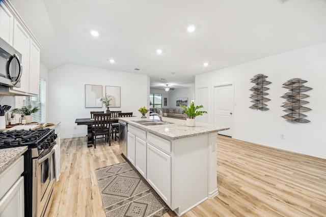 kitchen featuring appliances with stainless steel finishes, a sink, light wood-type flooring, a center island with sink, and white cabinets