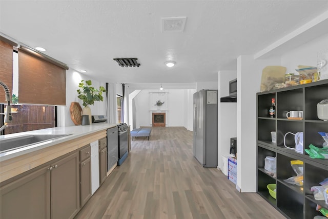10731 Sageberry Dr, Houston, TX 77089 - kitchen featuring freestanding refrigerator, a sink, light wood-style flooring, a fireplace, and light countertops