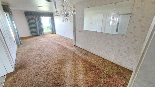 spare room with a chandelier, carpet flooring, and wallpapered walls