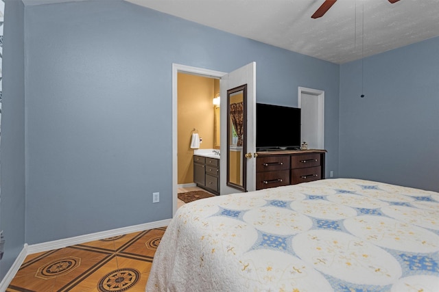 tiled bedroom featuring baseboards, ensuite bathroom, and ceiling fan