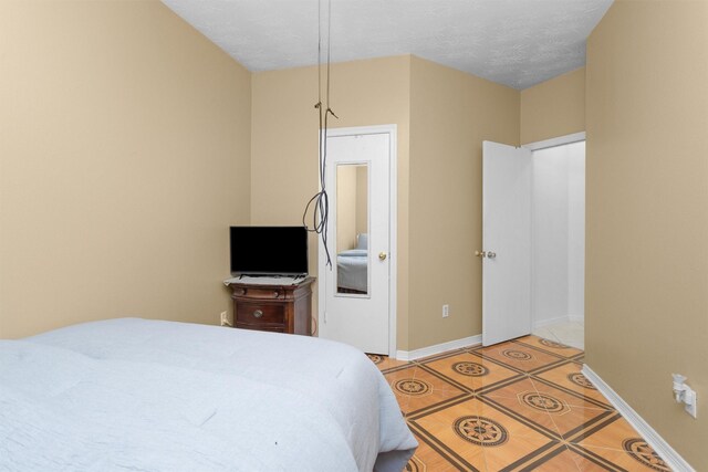 bedroom featuring light tile patterned flooring, baseboards, and a textured ceiling