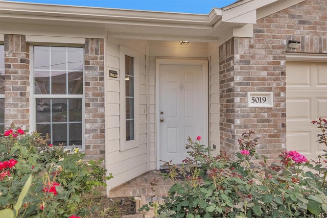 property entrance with brick siding and an attached garage