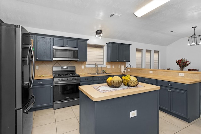 kitchen featuring appliances with stainless steel finishes, a sink, light countertops, light tile patterned flooring, and a peninsula