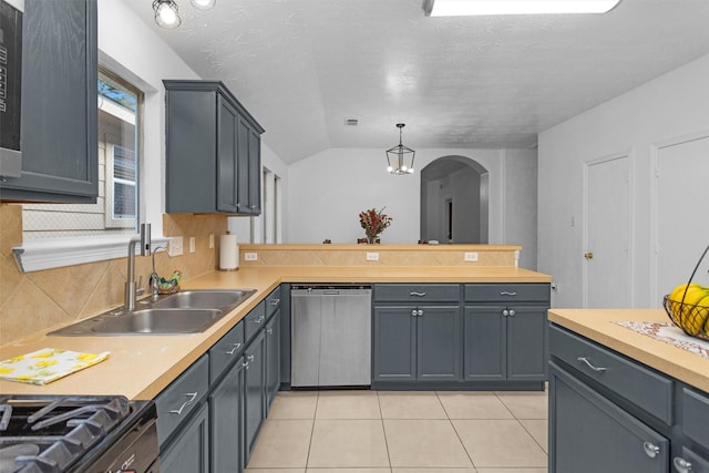kitchen featuring dishwasher, a sink, arched walkways, decorative backsplash, and light countertops