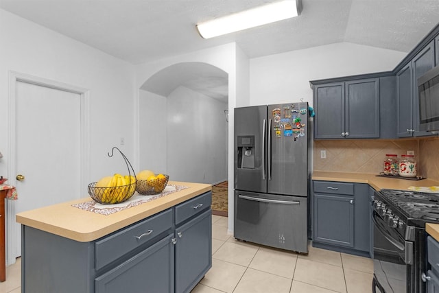 kitchen with stainless steel fridge, arched walkways, light countertops, lofted ceiling, and light tile patterned floors