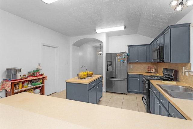 kitchen featuring stainless steel refrigerator with ice dispenser, gas range oven, arched walkways, a sink, and light tile patterned floors