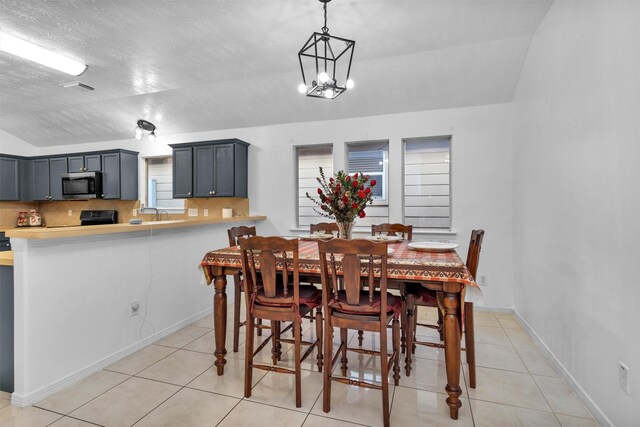 dining space with light tile patterned floors, vaulted ceiling, and a chandelier