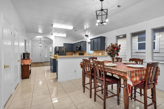 dining space featuring arched walkways, lofted ceiling, and light tile patterned floors