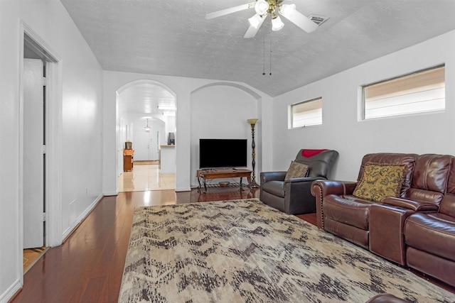 living room with arched walkways, ceiling fan, wood finished floors, a textured ceiling, and baseboards