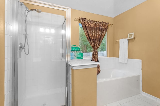 bathroom featuring a shower stall, a garden tub, and baseboards