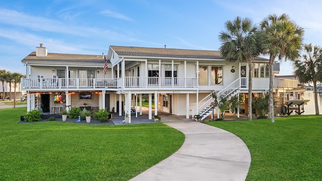 4321 Jolly Roger Rd, Galveston, TX 77554 - rear view of house featuring stairway, a yard, a chimney, driveway, and a shingled roof