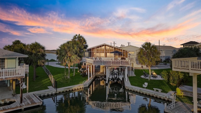 4321 Jolly Roger Rd, Galveston, TX 77554 - rear view of property with boat lift, a lawn, and a deck with water view