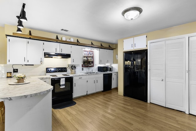 309 Kings Hl, Palacios, TX 77465 - kitchen featuring black appliances, under cabinet range hood, light countertops, backsplash, and a sink