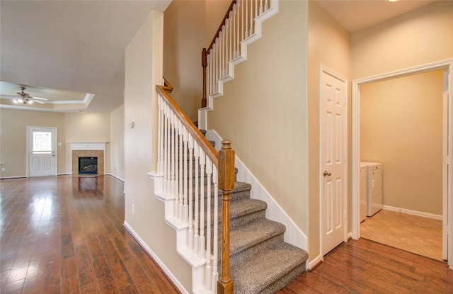 17607 Memorial Falls Dr, Tomball, TX 77375 - stairway with washer and dryer, a ceiling fan, hardwood / wood-style floors, a fireplace, and a tray ceiling
