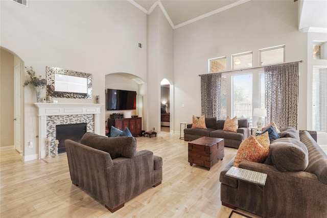 9612 Eden Ridge Ln, Pearland, TX 77584 - living area with arched walkways, crown molding, a fireplace, light wood-style flooring, and baseboards