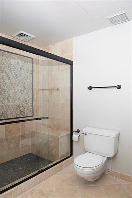 5050 Woodway Dr Unit 2A, Houston, TX 77056 - bathroom featuring a shower stall, toilet, baseboards, and tile patterned flooring