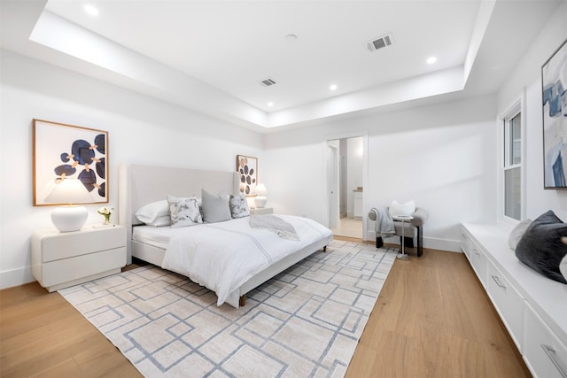 bedroom featuring a tray ceiling, light wood-style flooring, recessed lighting, and baseboards