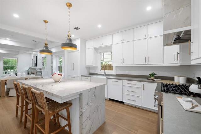 608 W Main St, Houston, TX 77006 - kitchen featuring stainless steel gas stove, a sink, light wood-type flooring, a kitchen island, and healthy amount of natural light