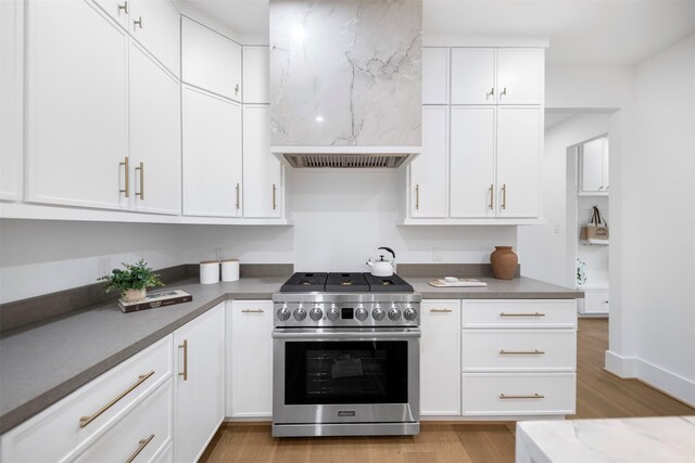 608 W Main St, Houston, TX 77006 - kitchen featuring stainless steel gas range oven, exhaust hood, light wood-style flooring, and white cabinets