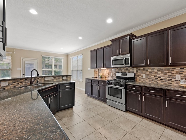 kitchen featuring appliances with stainless steel finishes, a sink, light tile patterned floors, backsplash, and crown molding