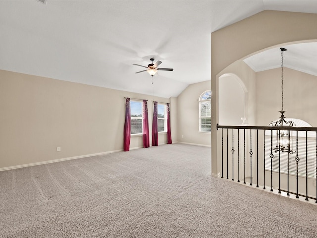 empty room featuring vaulted ceiling, ceiling fan, baseboards, carpet floors, and a chandelier