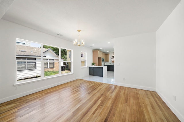 unfurnished living room featuring a chandelier, light wood-style flooring, baseboards, and recessed lighting