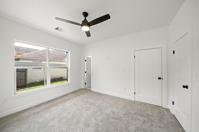 carpeted empty room featuring ceiling fan and baseboards