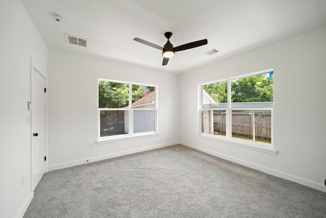 empty room featuring healthy amount of natural light, a ceiling fan, baseboards, and carpet flooring
