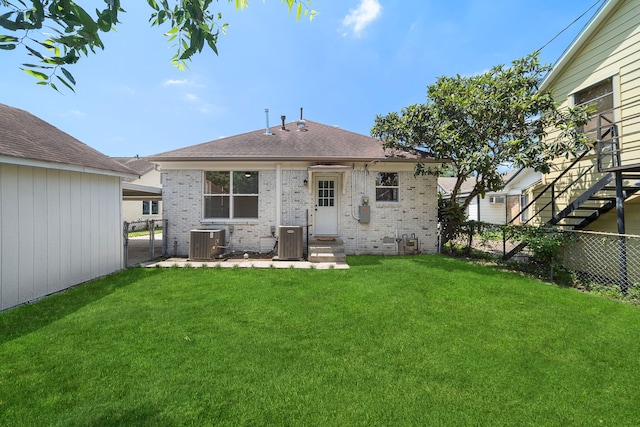back of property featuring central air condition unit, brick siding, and roof with shingles