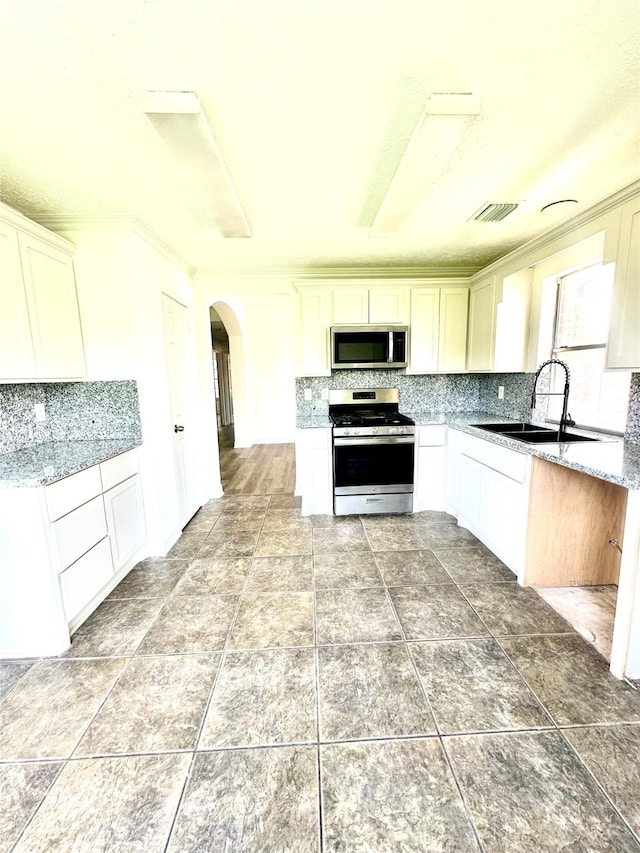 5006 Dawngate Dr, Spring, TX 77373 - kitchen featuring stainless steel appliances, arched walkways, tasteful backsplash, a sink, and ornamental molding