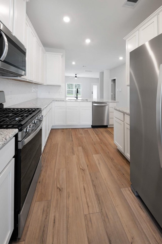 6171 White Spruce Dr, Conroe, TX 77304 - kitchen featuring stainless steel appliances, a sink, light wood-style flooring, white cabinets, and recessed lighting