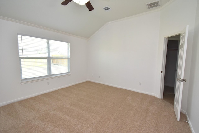 unfurnished bedroom featuring lofted ceiling, light colored carpet, ornamental molding, a spacious closet, and baseboards
