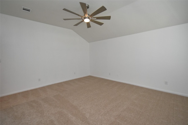 spare room featuring light colored carpet, a ceiling fan, lofted ceiling, and baseboards