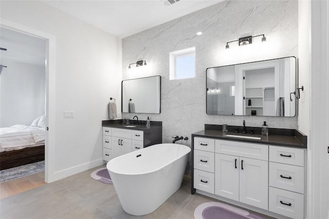 18605 Lakeland Dr, Point Venture, TX 78645 - ensuite bathroom with a freestanding bath, two vanities, and baseboards