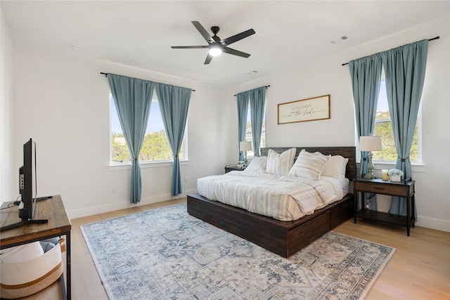 18605 Lakeland Dr, Point Venture, TX 78645 - bedroom with multiple windows, baseboards, light wood-type flooring, and a ceiling fan