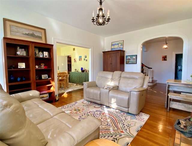 living room featuring arched walkways, wood finished floors, a chandelier, and stairs