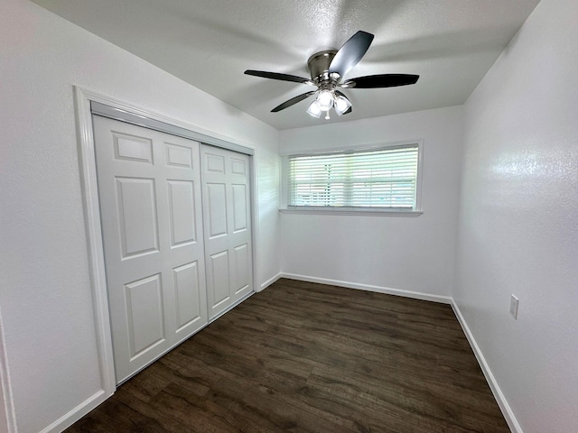 unfurnished bedroom featuring dark wood finished floors, baseboards, and a closet