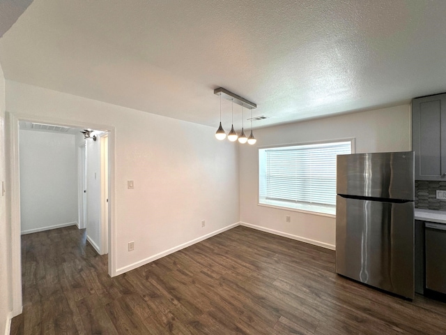 unfurnished dining area featuring dark wood-style flooring, baseboards, and a textured ceiling