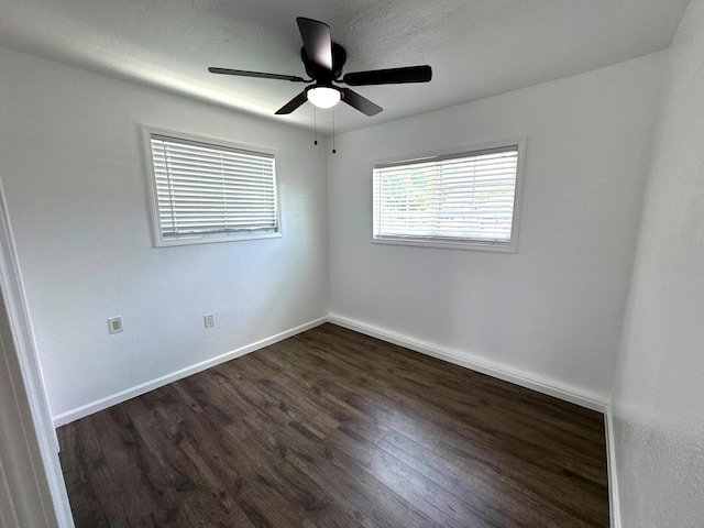 spare room with dark wood-style floors, ceiling fan, and baseboards