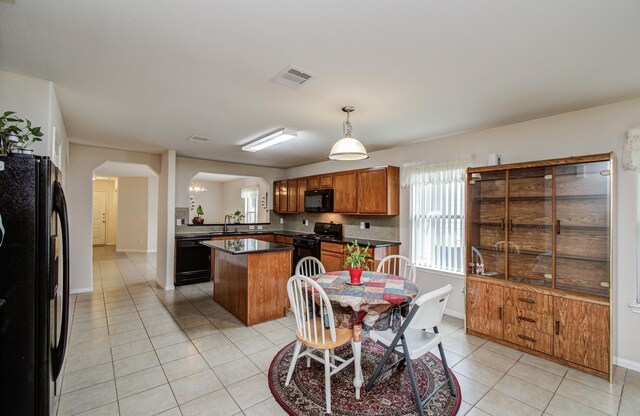 10406 Tenleyton Ln, Houston, TX 77075 - kitchen with black appliances, arched walkways, light tile patterned flooring, dark countertops, and a kitchen island
